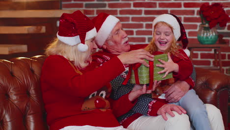 grandparents gifting christmas xmas present box to amazed happy granddaughter at home, celebrating