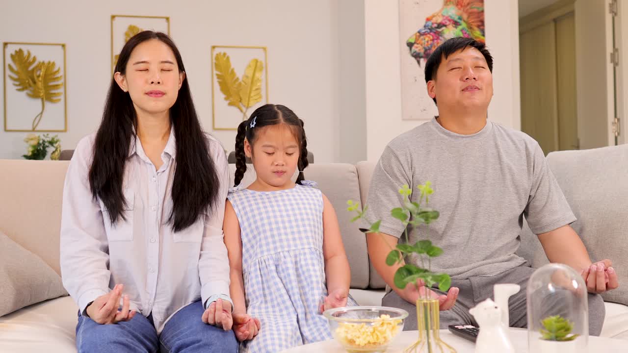 A family of three meditates together in a bright, serene living room, fostering calmness and connection