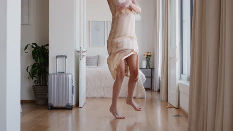 happy woman jumping on bed in hotel room having fun enjoying vacation lifestyle celebrating freedom