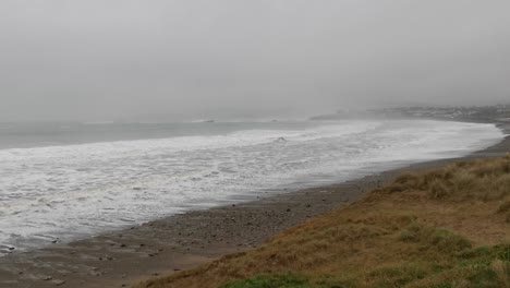 la niebla en un día tormentoso cubre una playa oceánica con fuertes vientos y olas