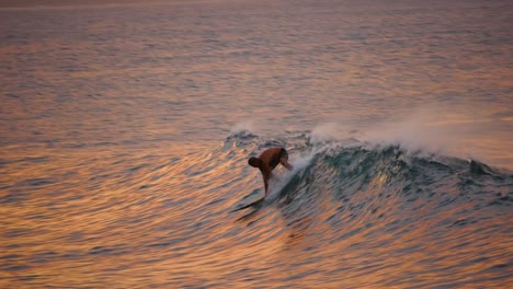 The-silhouette-of-a-lone-surfer-standing-up-on-his-board-as-the-sun-just-goes-down-on-North-Shore-Oahu-Hawaii