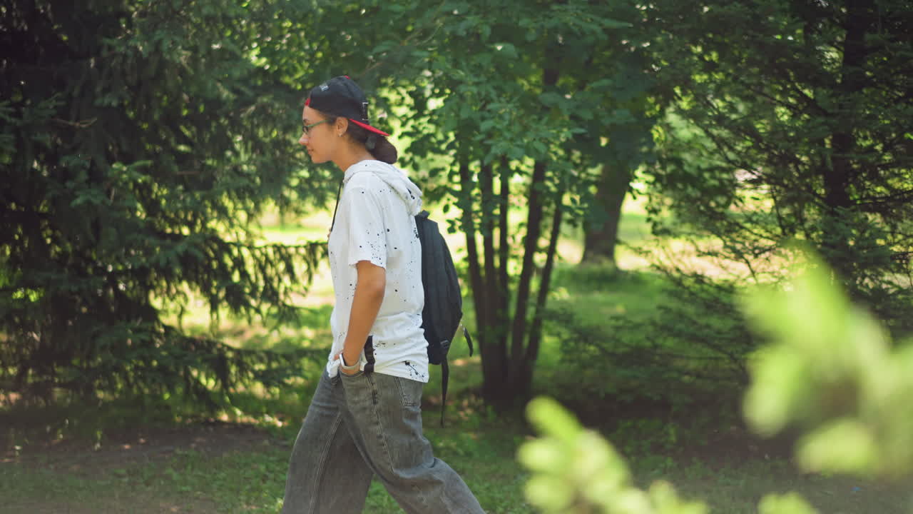 Teenager leisurely wanders through serene and tranquil green space, An energetic young individual enjoys gentle and peaceful walk beneath sheltering pine trees in tranquil park setting