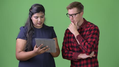 joven pareja de negocios multiétnica juntos contra un fondo verde