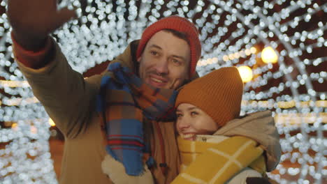 Joyous-Couple-Standing-in-Tunnel-of-Christmas-Lights