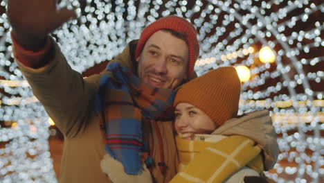 joyous couple standing in tunnel of christmas lights