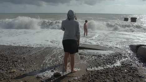 personas observando las olas en una playa tormentosa