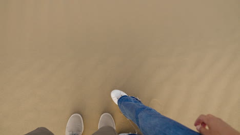 man and woman carefully walking on steep sand dunes in the desert