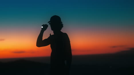 hiker shines flashlight around during sunset creating a chromatic flare. shot on canon r5 4k fine with rf 70-200mm f2.8 with chromatic flare filter.