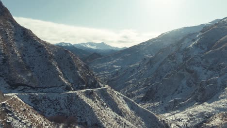 Aerial-fly-through-snowy-winter-mountains-in-canyon,-wide