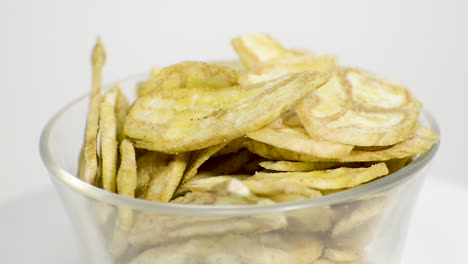 Detail-Der-Bananenchips-In-Einem-Glas,-Das-Sich-Auf-Einem-Weißen-Hintergrund-Dreht