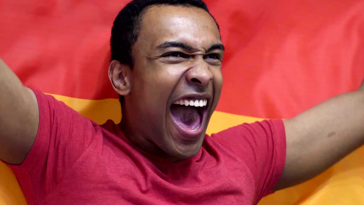 fanático alemán celebrando mientras sostiene la bandera de alemania en cámara lenta