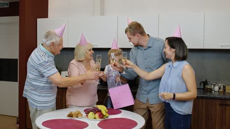 Mother,-father-and-grandparents-giving-gift-bag-for-child-girl.-Celebrating-birthday-anniversary