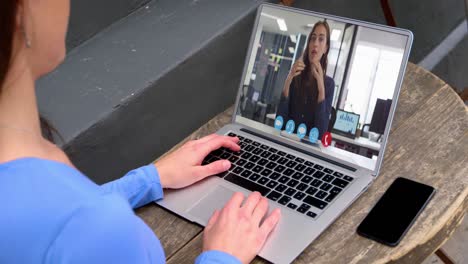 sección media de una mujer caucásica haciendo una videollamada con una colega en una computadora portátil