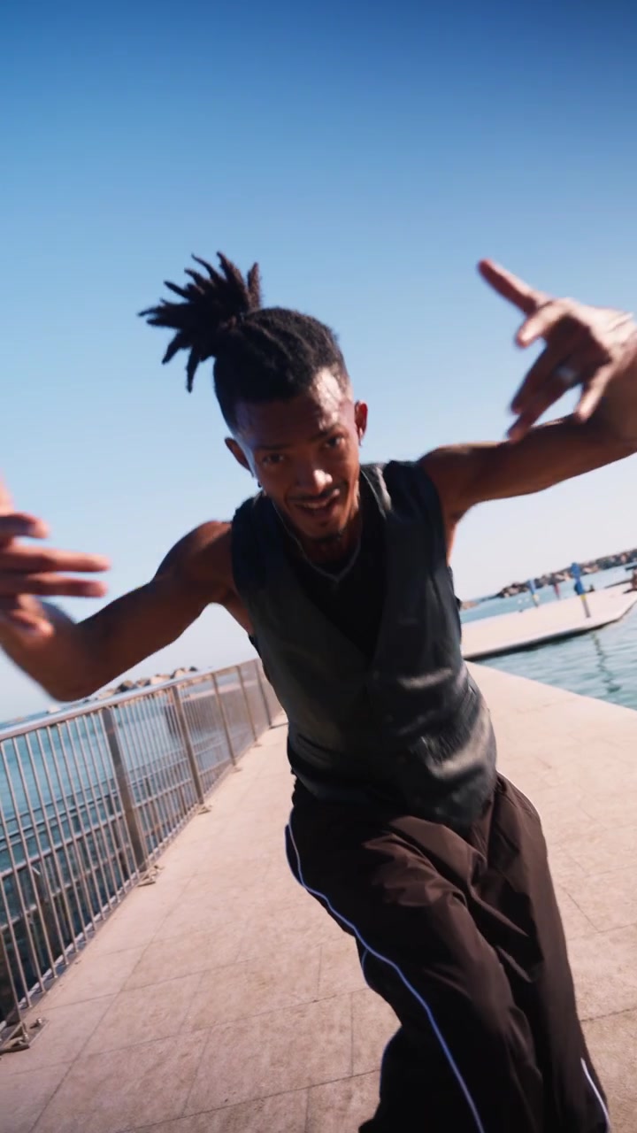 Giovane uomo che esegue street dance e un salto mortale all'indietro su un molo sul lungomare.