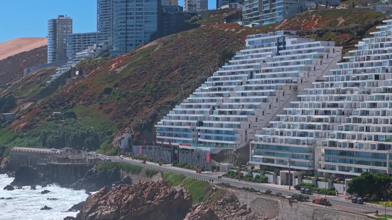 Vista aérea da orla marítima de Concón, com edifícios projetados no estilo arquitetónico de encosta chileno, num dia ensolarado.