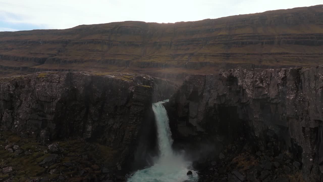 catarata de islandia en cascada sobre un acantilado de basalto negro al atardecer en otoño - revelación aérea de retroceso