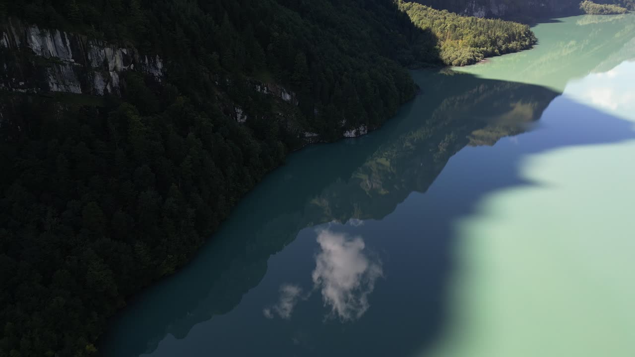 Sorvolando un lago, con un'ombra imponente che crea l'immagine di una gigantesca collina nella foresta sottostante, e un riflesso cristallino delle nuvole dal cielo, da qualche parte in Africa, senza nessuno intorno