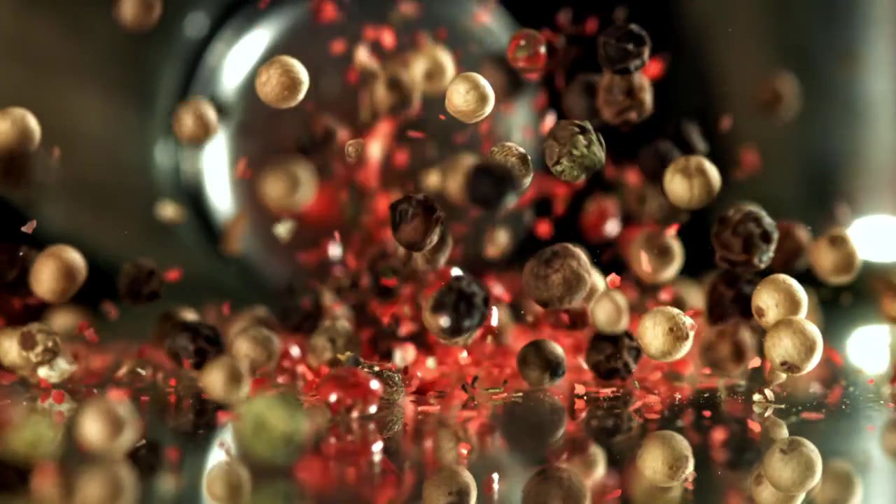 Misto di grani di pepe e scaglie rosse che cadono in super slow motion