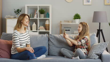 Teenager-Hübsches-Mädchen-Mit-Langen-Blonden-Haaren,-Das-Fotos-Ihrer-Charmanten-Mutter-Auf-Dem-Smartphone-Im-Wohnzimmer-Macht