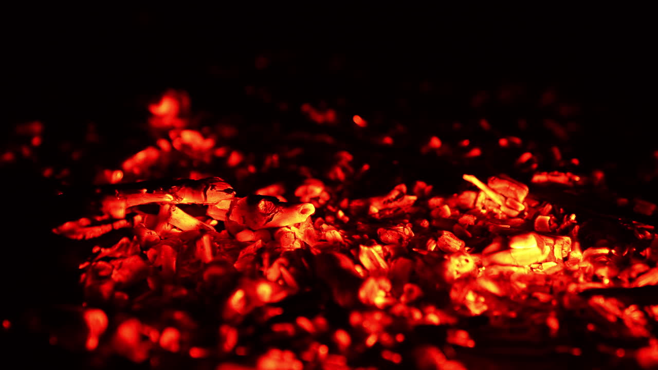 Red hot smoldering pieces of burnt out wood. Little fire flame splashes on the charcoal. Close up.