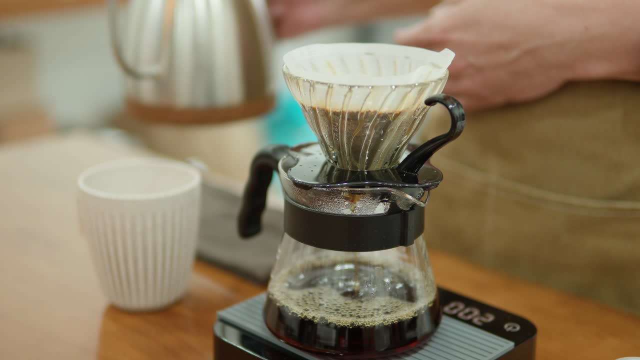 Barista Brewing Hand Drip Coffee - Man's Hands Pouring Hot Water from Drip Kettle Into Coffee Dripper on Drip Scale