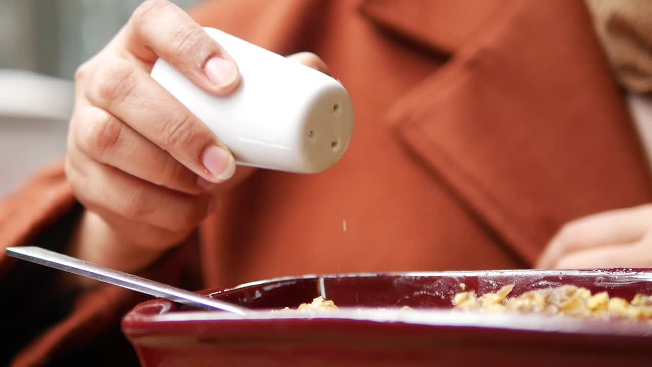 mujer añadiendo sal a la comida