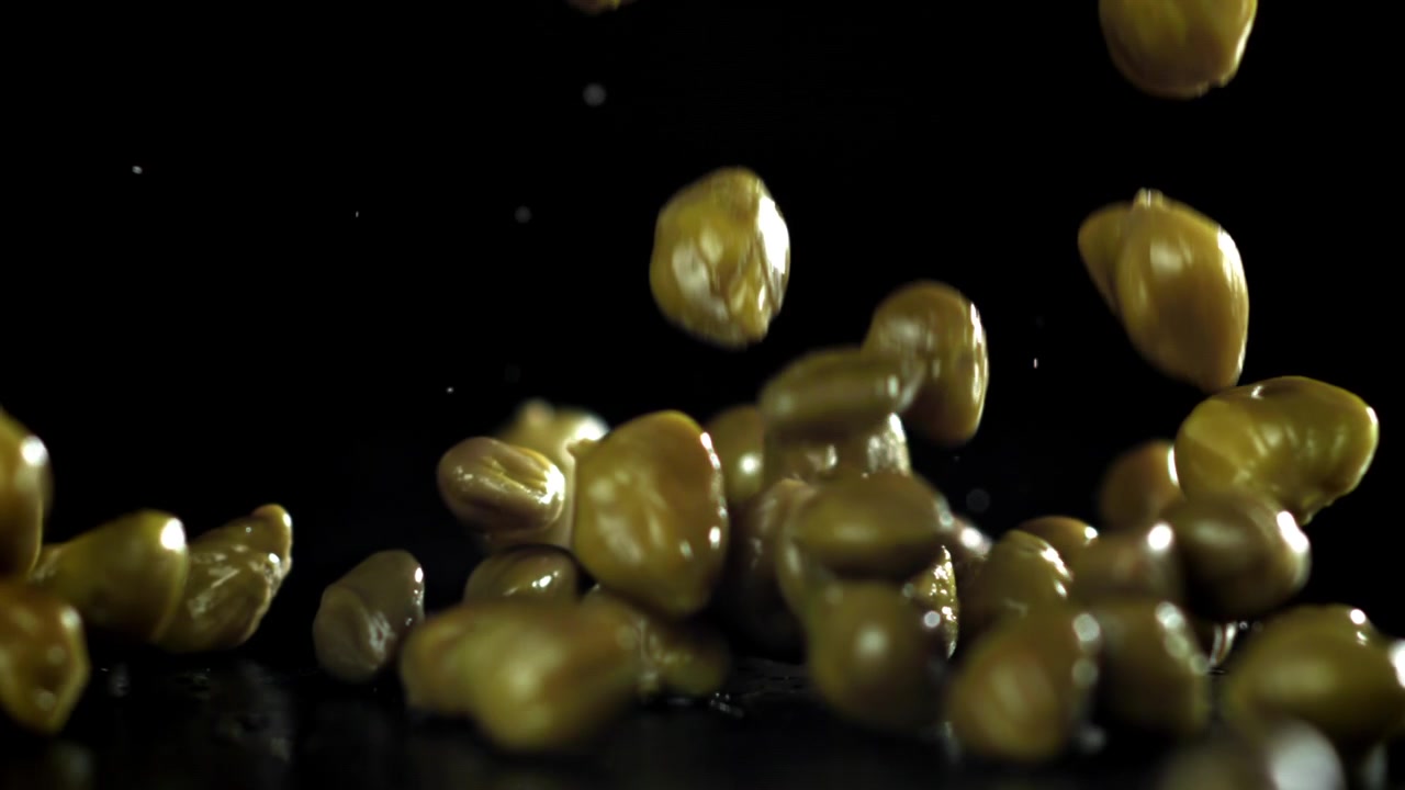 Capperi sottaceto che cadono su sfondo nero al rallentatore