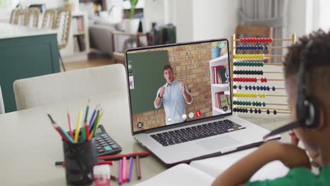 composition of african american boy on laptop online learning with caucasian male teacher