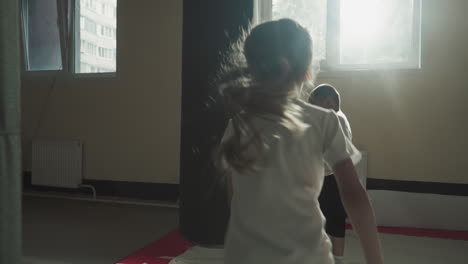 children exercise with punching bags in sports club. little martial arts students girl and boy train kickboxing techniques in fighting gym slow motion. junior fighters