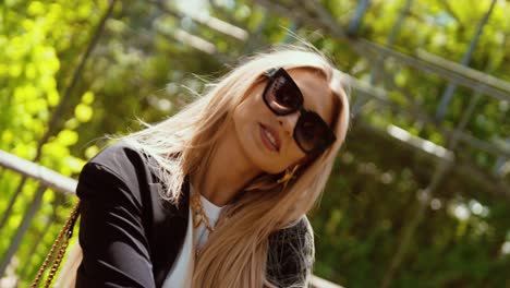 young blonde attractive woman in a park smiling and posing
