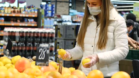 A blonde girl chooses oranges in the market. A young woman is shopping, she buys fresh fruit. High quality 4k footage