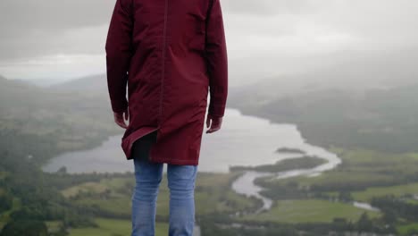 young man turning to look the fantastic landscape with mountain range and lake in scotland