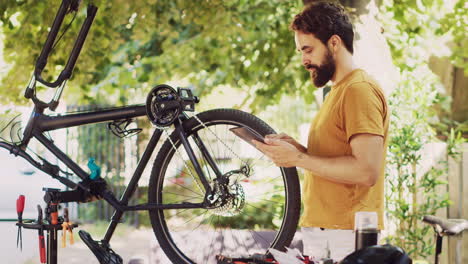 Sporty-man-upkeeps-bicycle-with-tablet