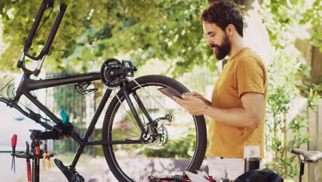 sporty man upkeeps bicycle with tablet