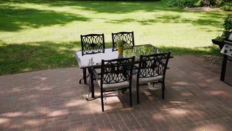 panning reveal shot of an outdoor patio dinner table next to a grill on a sunny day