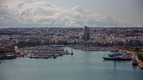 the city of valletta, malta and the harbor with many boats docked - cloudscape time lapse