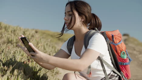 side view of teenaged girl taking picture of exotic plant with phone