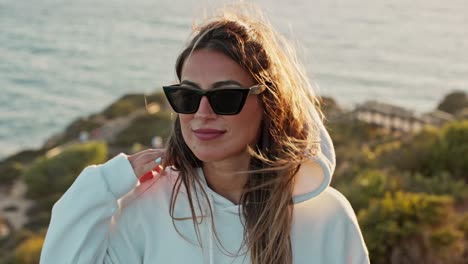 disparo en cámara lenta de una chica atractiva en la costa durante el atardecer con su cabello soplando