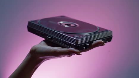 hand holding a portable disc player on a purple background