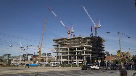 lapso de tiempo de construcción y movimiento de grúas con tráfico de vehículos en primer plano