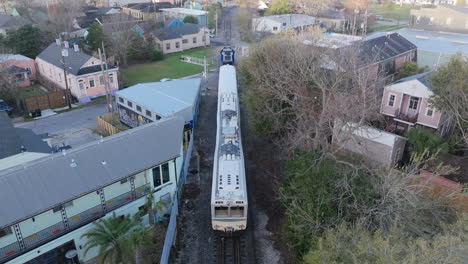 aerial video following a slow moving passenger train outside the outskirts of downtown new orleans