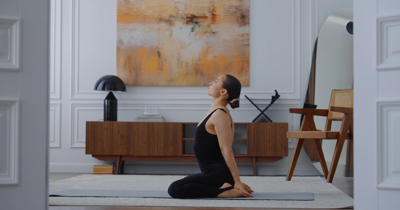 Kvinde udfører yogastræk på måtte i moderne stue