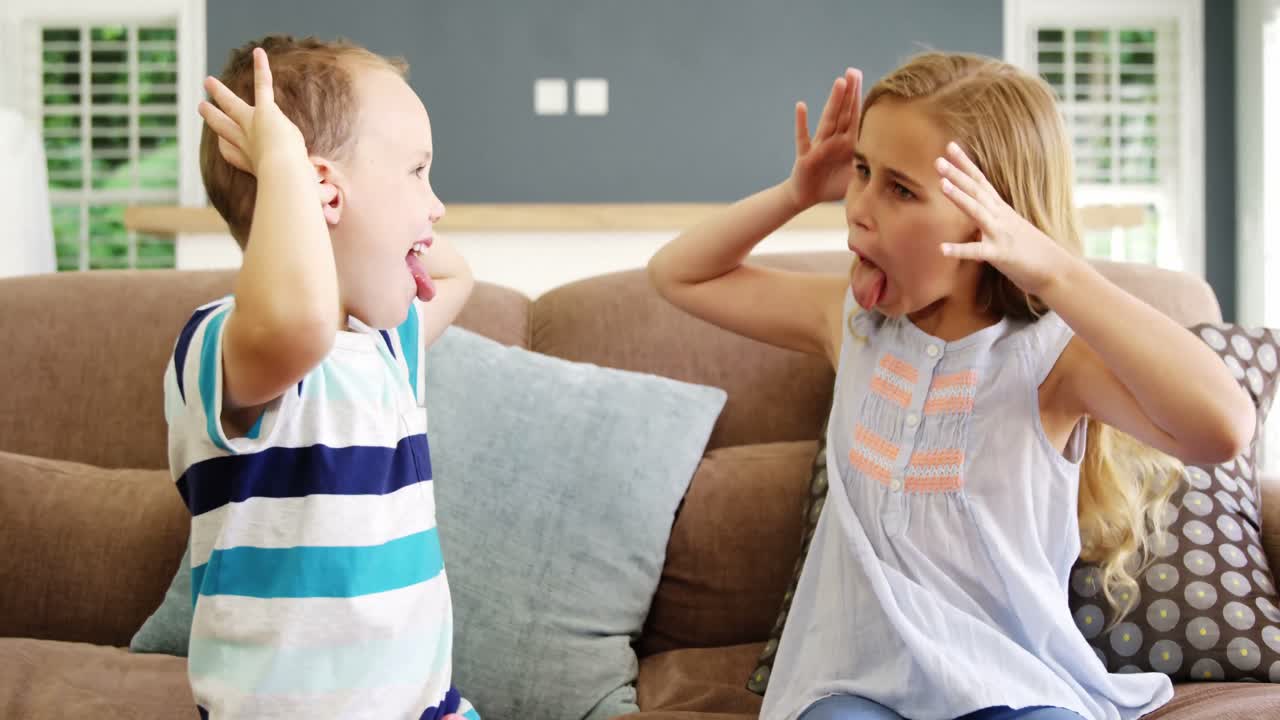 Boy and girl sitting on sofa teasing each other