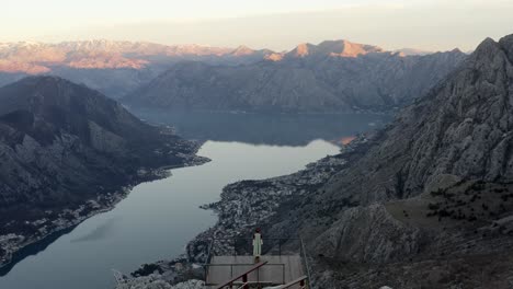 woman in traditional montenegrin dress standing on wooden deck and enjoying the birds eye view of kotor bay