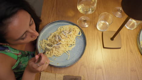 woman eating spaghetti for dinner at the restaurant under cozy light