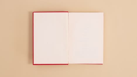 el libro vintage de tapa dura roja aparece y se abre con espacio de copia en fondo beige.