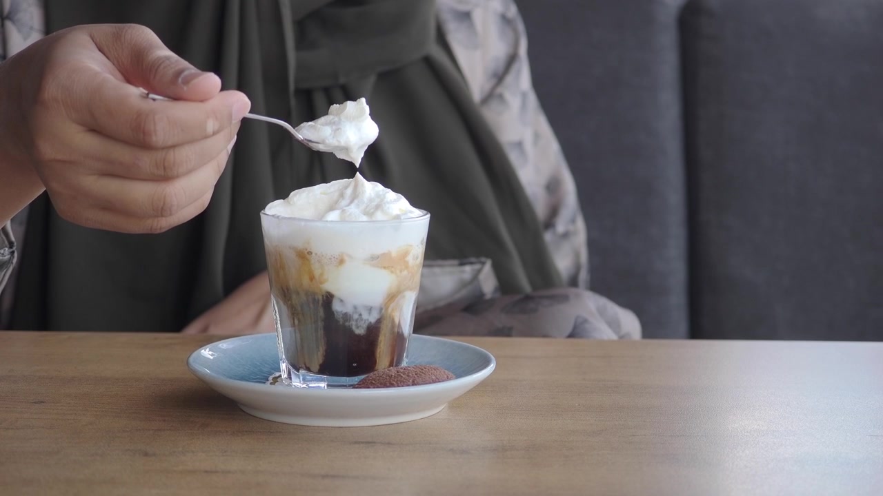 Persona comiendo crema batida de un vaso de café