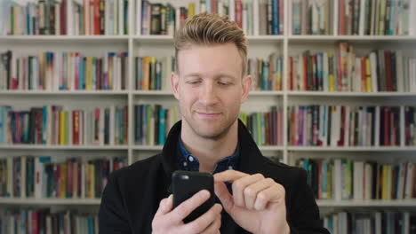 portrait-of-young-confident-businessman-entrepreneur-in-library-study-texting-browsing-online-using-smartphone-technology