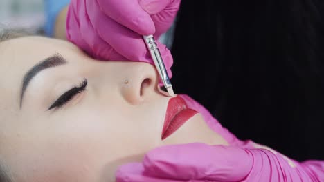 the master in rubber gloves brushes the contour of the lips of a young girl