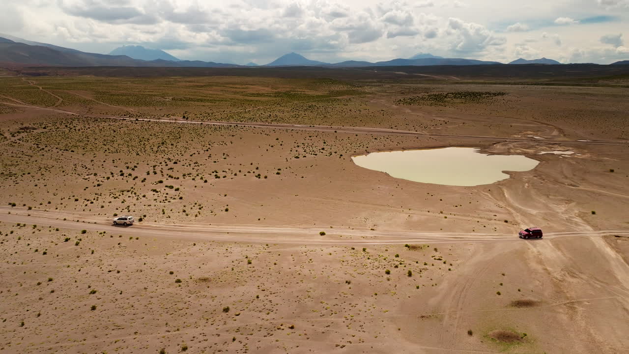 Ecotourism in Siloli desert in Bolivia as cars drive on dirt track, aerial view